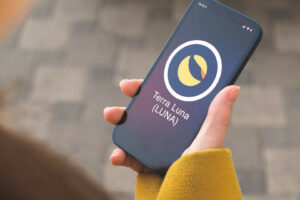 Terra Luna cryptocurrency symbol, logo. Business and financial concept. Hand with smartphone, screen with crypto icon closeup